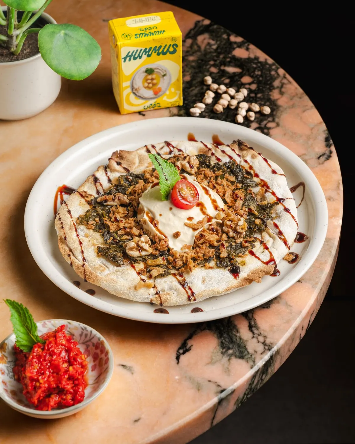 A flatbread topped with labneh, crispy onion, walnuts, and herbs